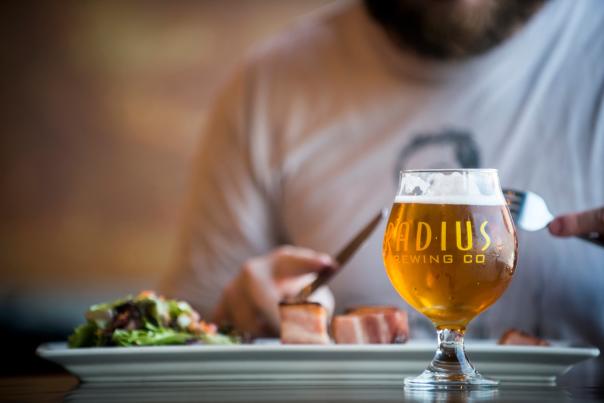 Man enjoys a meal and a beer at Radius Brewing