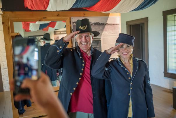 A man and woman dressed up in historic soldier uniforms salutes the camera at Fort Hays State Historic Site.