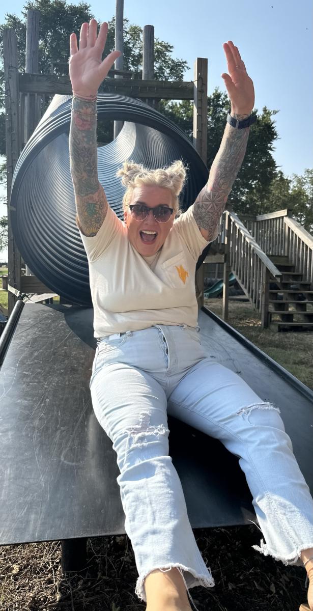 Woman goes down a slide at a farm