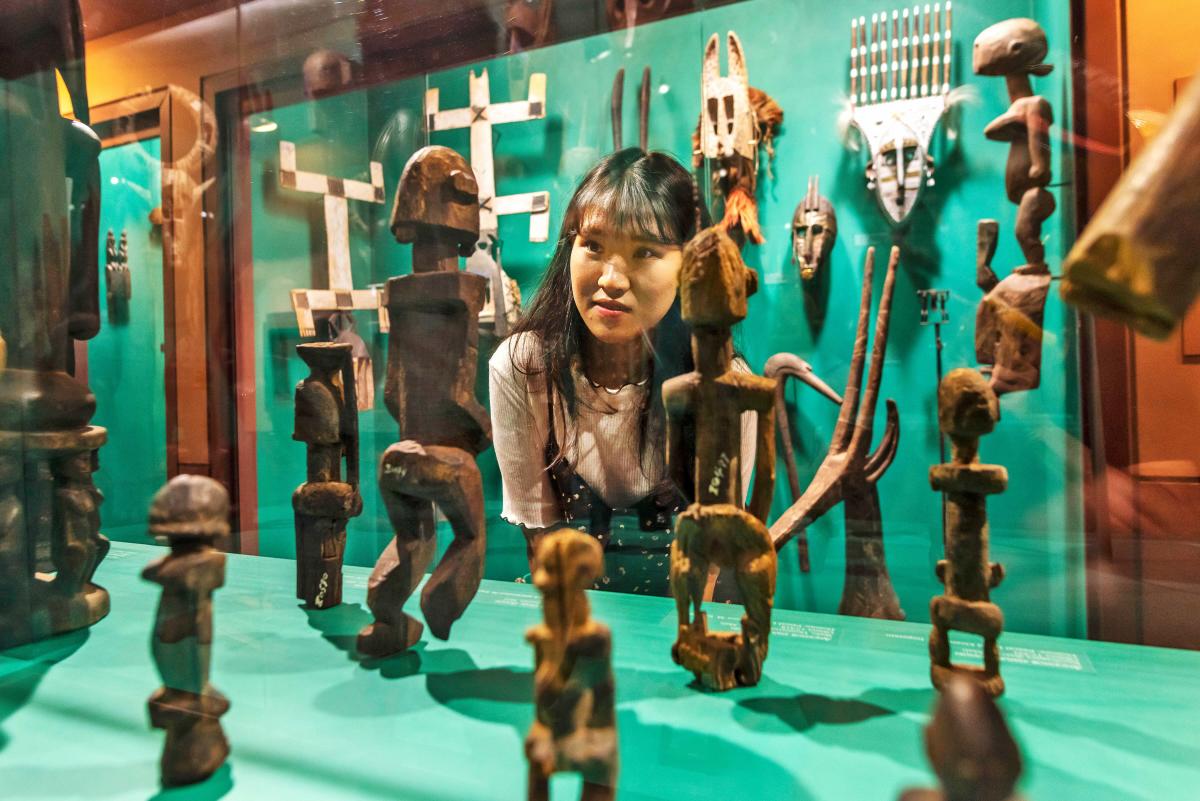 Girl looks at display of various stone items in Safari Museum